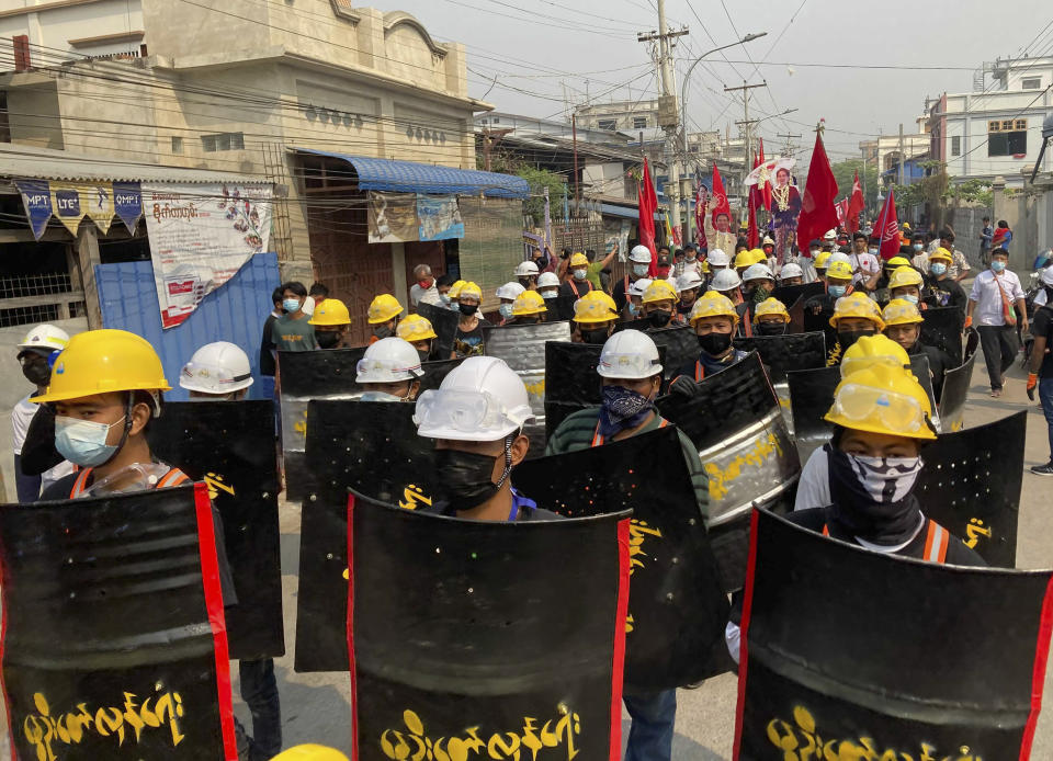 Protesters march with makeshift shields on a main road during a demonstration in Mandalay, Myanmar, Monday, March 8, 2021. Large protests have occurred daily across many cities and towns in Myanmar. (AP Photo)