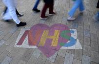 Shoppers walk past a mural denoting appreciation for the UK National Health Service, amidst the spread of the coronavirus disease (COVID-19) pandemic, in London