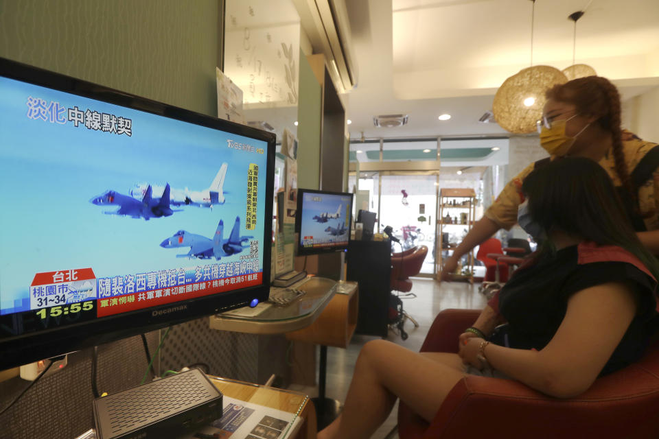 A customer and a staff member watch a news report on the recent tensions between China and Taiwan, at a beauty salon in Taipei, Taiwan, Thursday, Aug. 4, 2022. Taiwan canceled airline flights Thursday as the Chinese navy fired artillery near the island in retaliation for a top American lawmaker’s visit. (AP Photo/Chiang Ying-ying)