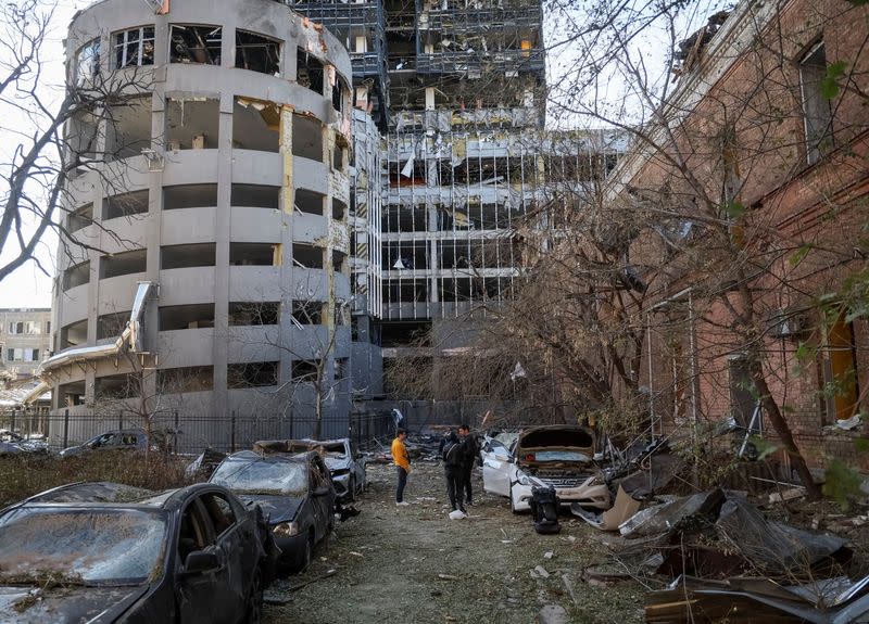 Local residents stand next to their car, destroyed by the previous day's Russian military strike, as Russia's attack on Ukraine continues, in central Kyiv