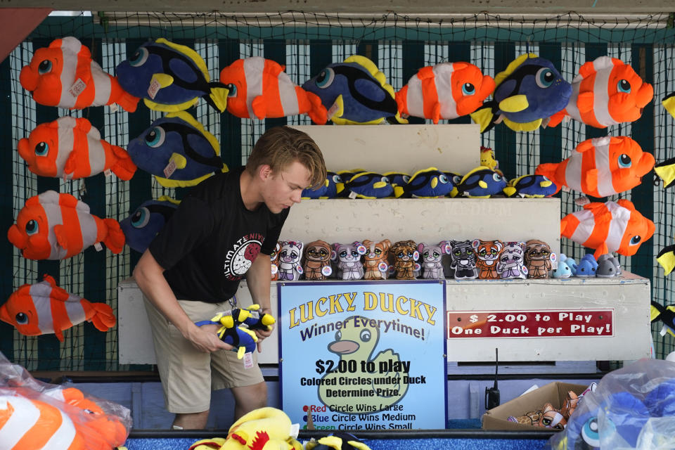 Parker Todd sets up a display of stuffed prizes at the Duck game at Funtown amusement park ahead of opening day, Wednesday, May 26, 2021, in Saco, Maine. The park, which was closed last season because to the COVID-19 pandemic, plans to operate only five days a week due to a worker shortage. (AP Photo/Robert F. Bukaty)