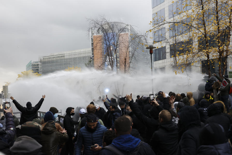 Riot police uses a water canon against protestors during a demonstration against the reinforced measures of the Belgium government to counter the latest spike of the coronavirus in Brussels, Belgium, Sunday, Nov. 21, 2021. Many among them also protested against the strong advice to get vaccinated and any moves to impose mandatory shots. (AP Photo/Olivier Matthys)
