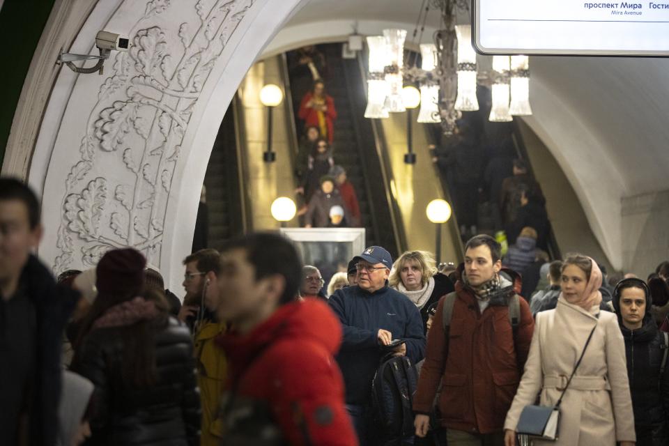 In this photo taken on Saturday, Feb. 22, 2020, a surveillance camera, top left, is seen as people walk down in a Moscow's Metro (subway) station in Moscow, Russia. Metro workers were instructed to stop passengers from China and ask them to fill out a questionnaire about the purpose of their visit to Russia, address of residence, health condition and whether they underwent quarantine upon arrival. (AP Photo/Alexander Zemlianichenko)