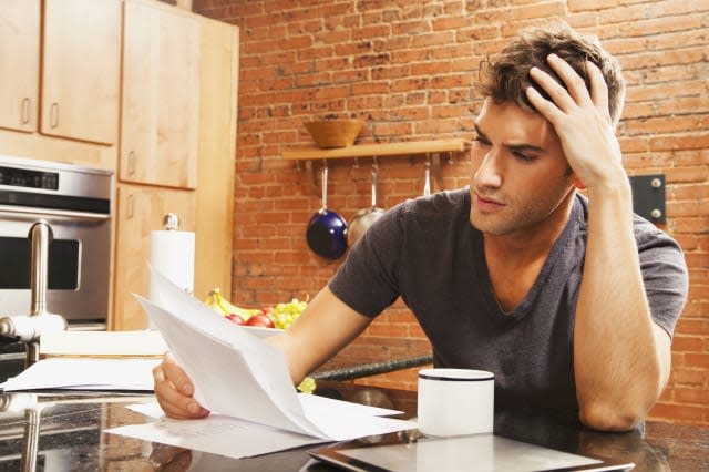 Caucasian man looking at paperwork in kitchen