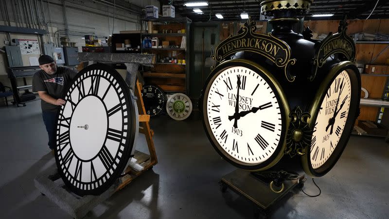 Dan LaMoore rolls a tower clock face across the plant floor at Electric Time Company on Oct. 23, 2020, in Medfield, Mass.