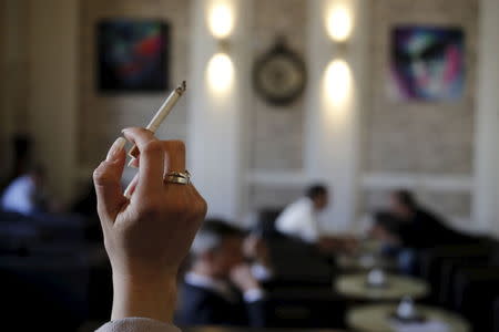 A women holds a cigarette in a cafe in Vienna April 10, 2015. REUTERS/Leonhard Foeger