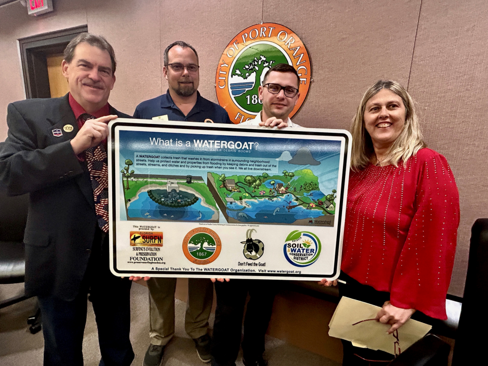 Port Orange Mayor Don Burnette, City Council members Tracy Grubbs and Reed Foley, and Environmental Advisory Board Chair Kristine Cunningham hold sign illustrating how a Watergoat works.