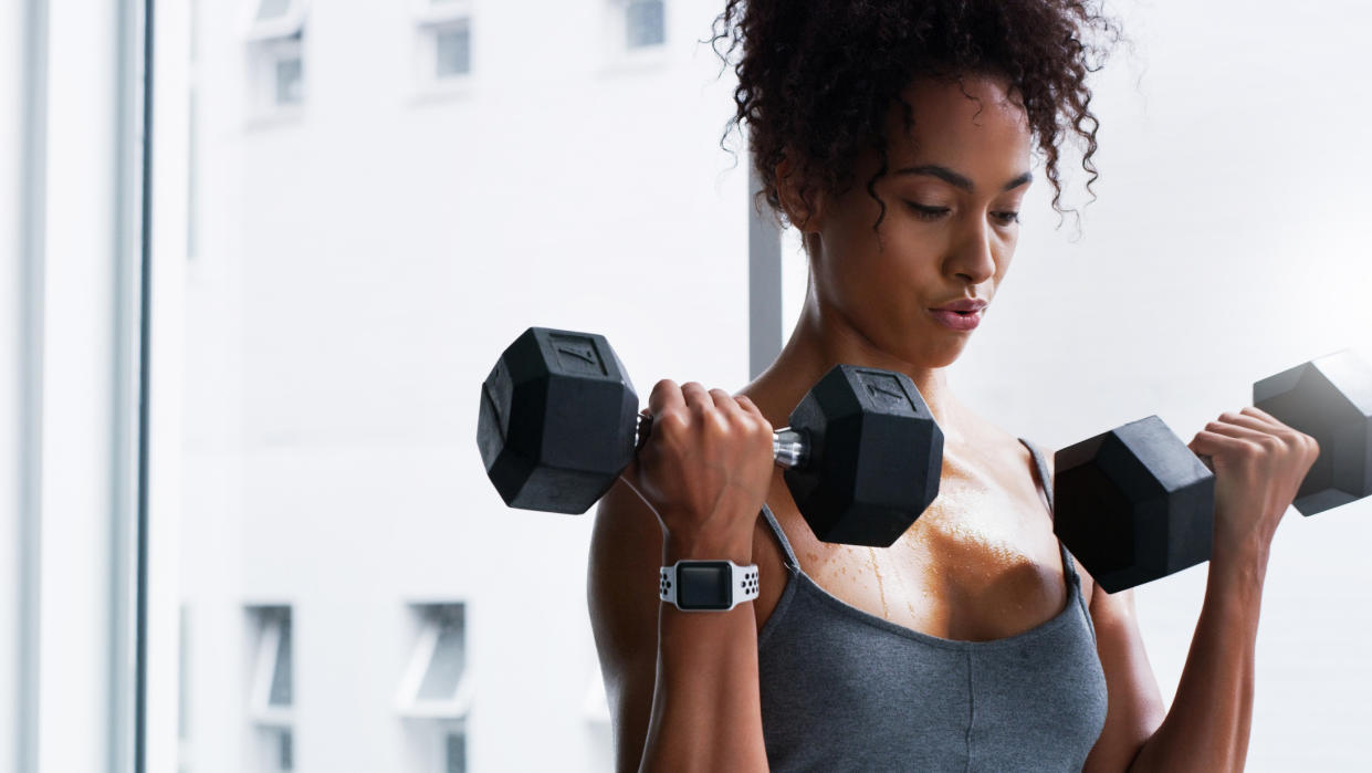  Woman performs biceps curl exercise with dumbbells. 