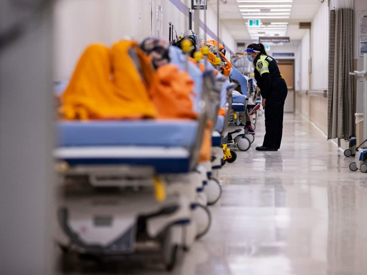 A paramedic checks on a patient waiting in the hallway of the Humber River Hospital emergency department in Toronto on Jan. 13, 2022. (Evan Mitsui/CBC - image credit)