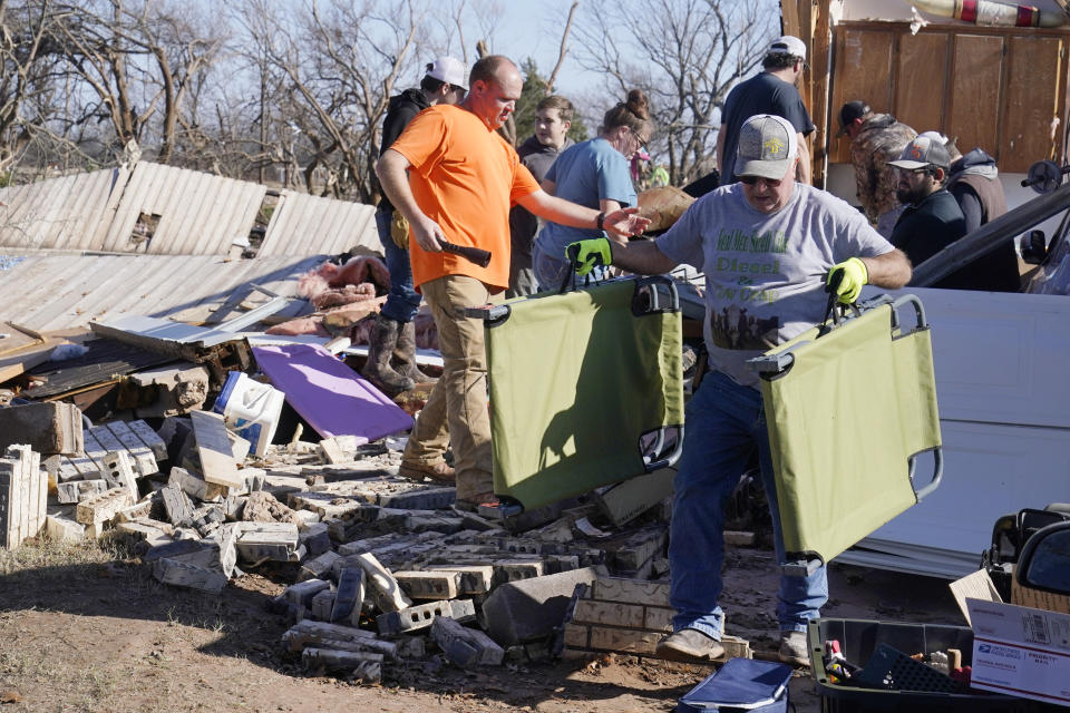 Bob Blackwell carries belongings from his daughter's home, destroyed by a tornado, Tuesday, Dec. 13, 2022, in Wayne, Okla. (AP Photo/Sue Ogrocki)