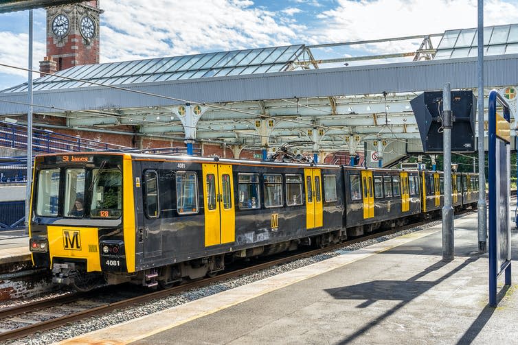 Yellow and black light rail train in station.