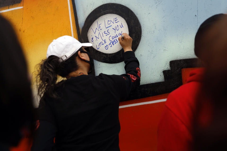 People write on a mural as they attend a peace walk honoring the life of police shooting victim 13-year-old Adam Toledo, Sunday, April 18, 2021, in Chicago's Little Village neighborhood. (AP Photo/Shafkat Anowar)