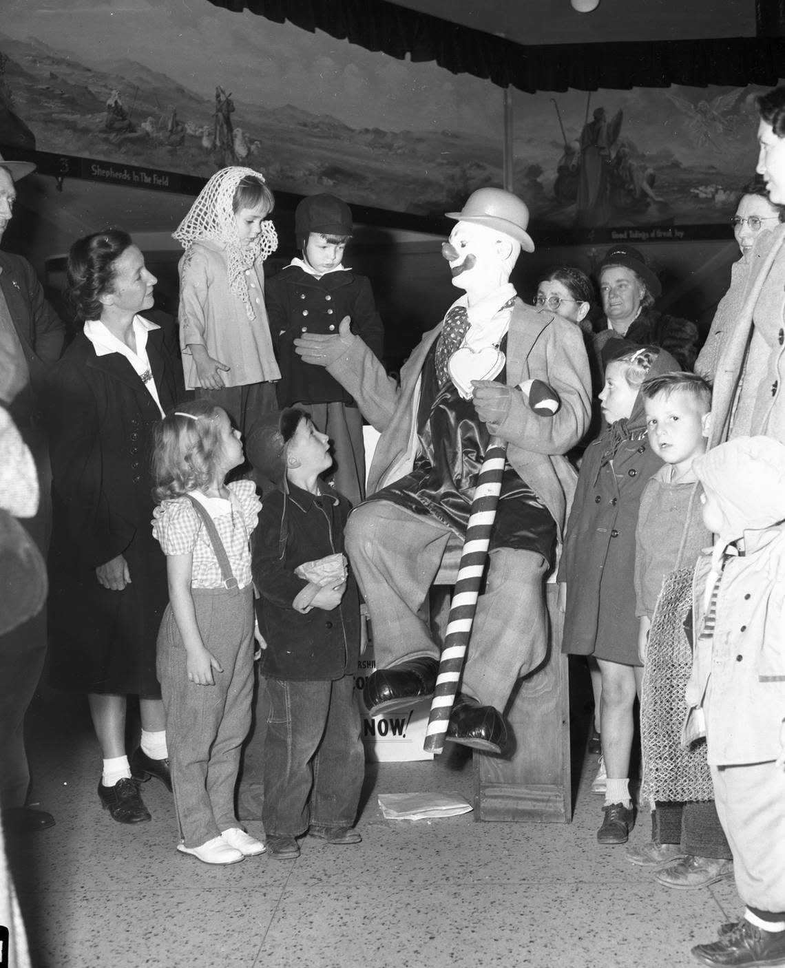 Dec. 5, 1945: Teamed with Santa Claus again to provide merry moments for struggling Christmas shoppers and the youngsters who accompany them is Paul Jung, circus clown. He is going through one of his many acts for a typical group of children at Leonard Brothers department store. The children on the table are Christine Clark, left, and Norman Webb. The others, left to right, are Gwenda Sue Lamb, Gerald Wayne Thompson, Sarah Jean Stephenson and Richard Garrett.