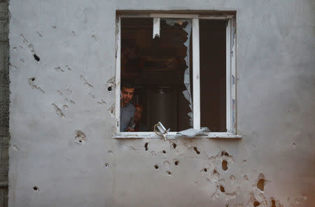 People look out from a building which was damaged after a rocket fired from Syria landed nearby, in the border town of Kilis, Turkey January 22, 2018. REUTERS/Osman Orsal