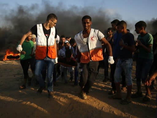 Palestinian protesters and rescuers carry a wounded protester during a demonstration along the Israel-Gaza border on August 3, 2018