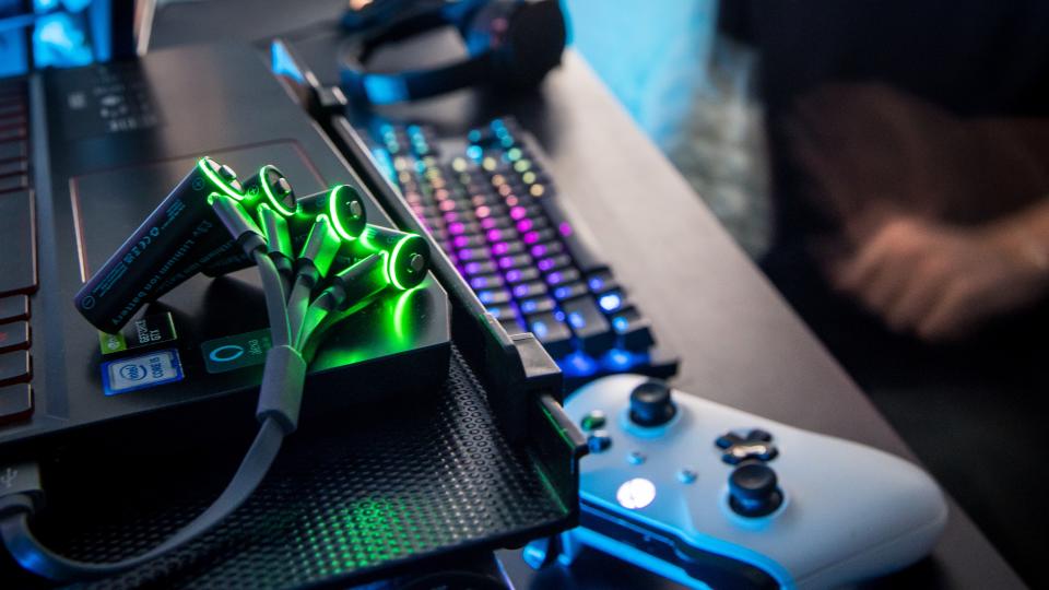 Paleblue batteries charging beside a game controller and keyboard