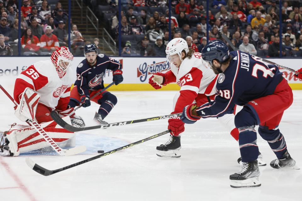 Detroit Red Wings' Ville Husso, left, makes a save as teammate Moritz Seider, center, defends against Columbus Blue Jackets' Boone Jenner during the second period of an NHL hockey game, Saturday, Nov. 19, 2022, in Columbus, Ohio.