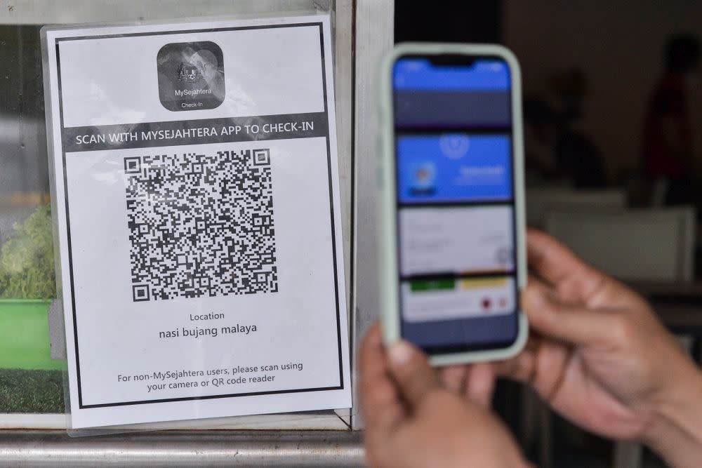 A user scans a QR code via the MySejahtera app at a restaurant in Shah Alam March 31, 2022. Starting May 1, Malaysians no longer need to scan using the MySejahtera contact tracing application to enter premises. — Picture by Miera Zulyana