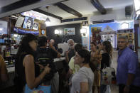 People gather inside the Bar Nilo where a makeshift shrine of soccer legend and former Napoli player Diego Armando Maradona is displayed in downtown Naples, Italy, Wednesday, Sept. 18, 2019. Alcide Carmine, right, owner of Bar Nilo said in an interview with the Associated Press, “For us, Maradona is more than a man. He’s a god. We Neapolitans love football and live for football." (AP Photo/Gregorio Borgia)