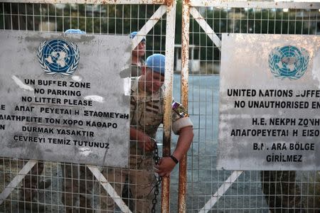 A U.N. soldier locks a gate inside the UN-controlled buffer zone in Nicosia, Cyprus June 28, 2017. REUTERS/Yiannis Kourtoglou