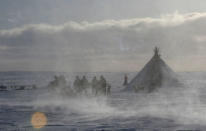 Members of the indigenous community "Yamb To" (Long Lake) greet a helicopter carrying local electoral commission officials during the early voting in remote areas ahead of the presidential election, at a reindeer camping ground, about 450 km northeast of Naryan-Mar, in Nenets Autonomous District, Russia, March 1, 2018. REUTERS/Sergei Karpukhin