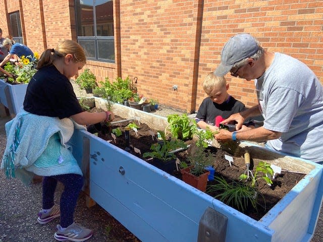 Boys & Girls Club members Cory Herr, left, and Tate Snell learn how to plant seedlings from Master Gardener Ernie Wight.