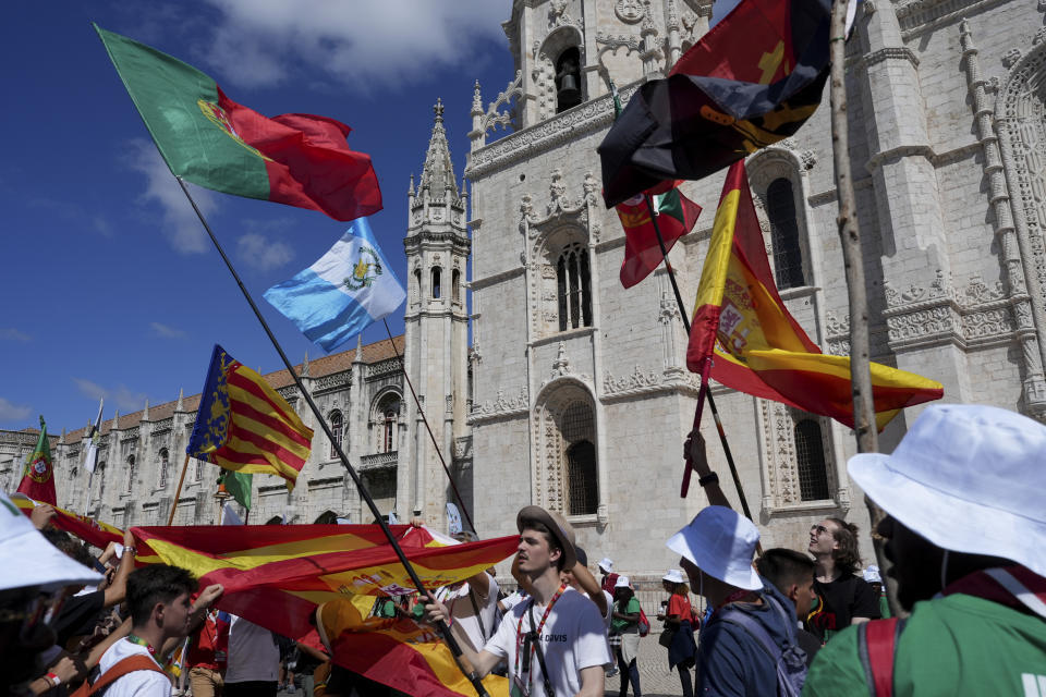 Pilgrims from different countries, travelling to participate in the World Youth Day, wave flags outside the 16th century Jeronimos monastery in Lisbon, Portugal, Tuesday, Aug. 1, 2023. Pope Francis will visit the monastery when he arrives Aug. 2 to attend the international event that is expected to bring hundreds of thousands of young Catholic faithful to Lisbon and goes on until Aug. 6. (AP Photo/Ana Brigida)