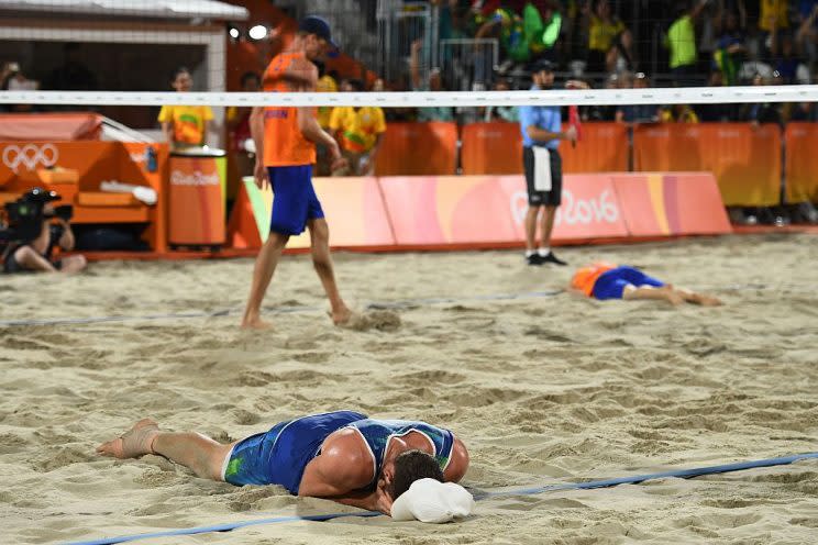 Brazil's Alison Cerutti (L) celebrates as Netherlands' Alexander Brouwer (R) and Netherlands' Robert Meeuwsen (C) react after the men's beach volleyball semi-final match between Brazil and the Netherlands at the Beach Volley Arena in Rio de Janeiro on August 16, 2016, as part of the Rio 2016 Olympic Games. / AFP / Leon NEAL (Photo credit should read LEON NEAL/AFP/Getty Images)