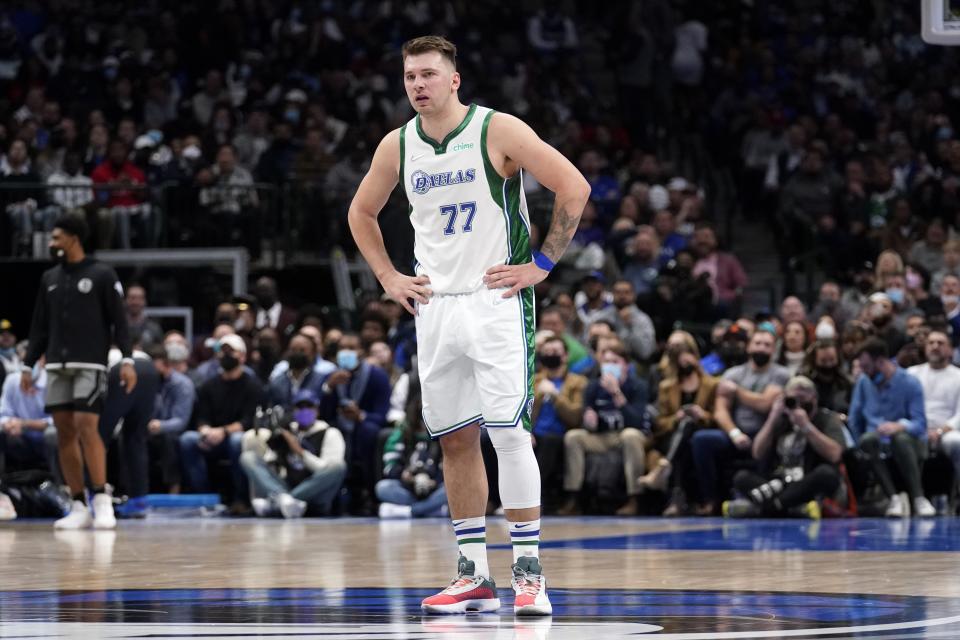 Dallas Mavericks guard Luka Doncic stands on the court looking at play after being knocked to the ground taking a shot in the second half of an NBA basketball game against the Brooklyn Nets in Dallas, Tuesday, Dec. 7, 2021. No foul was called against the Nets on Doncic's shot. (AP Photo/Tony Gutierrez)