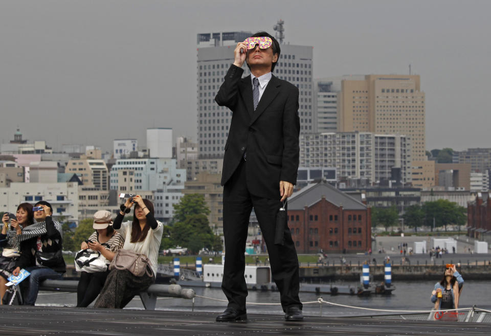 FILE - In this May 21, 2014 file photo, a business man watches an annular solar eclipse at a waterfront park in Yokohama, near Tokyo. The first solar eclipse of the year happens Tuesday, April 29, 2014, and will be visible to skygazers in Antarctica, Australia, and the southern Indian Ocean about 0600 GMT (2 a.m. EDT). The eclipse Tuesday is a rare type of annular eclipse, meaning the sun will appear as a ring around the moon. (AP Photo/Shuji Kajiyama, File)