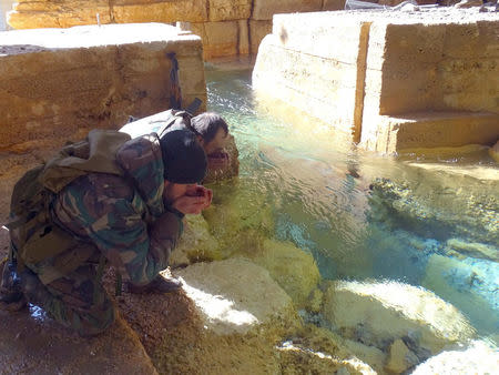 Syrian government soldiers drink from a water pumping station in the village of Ain al-Fija in the Wadi Barada valley near Damascus, Syria in this handout picture provided by SANA on January 29, 2016. SANA/Handout via REUTERS