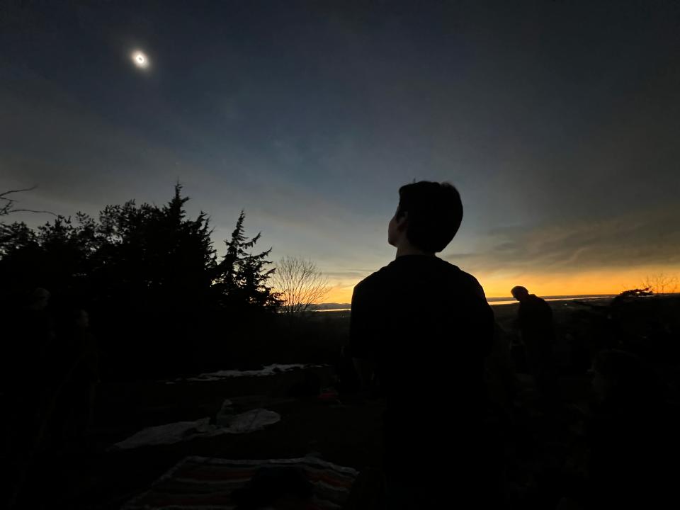 Xander Barton, 13, stares up during totality of the solar eclipse from a Williston, Vermont overlook. Williston students got the day off from school for the occasion Monday, April 8, 2024.