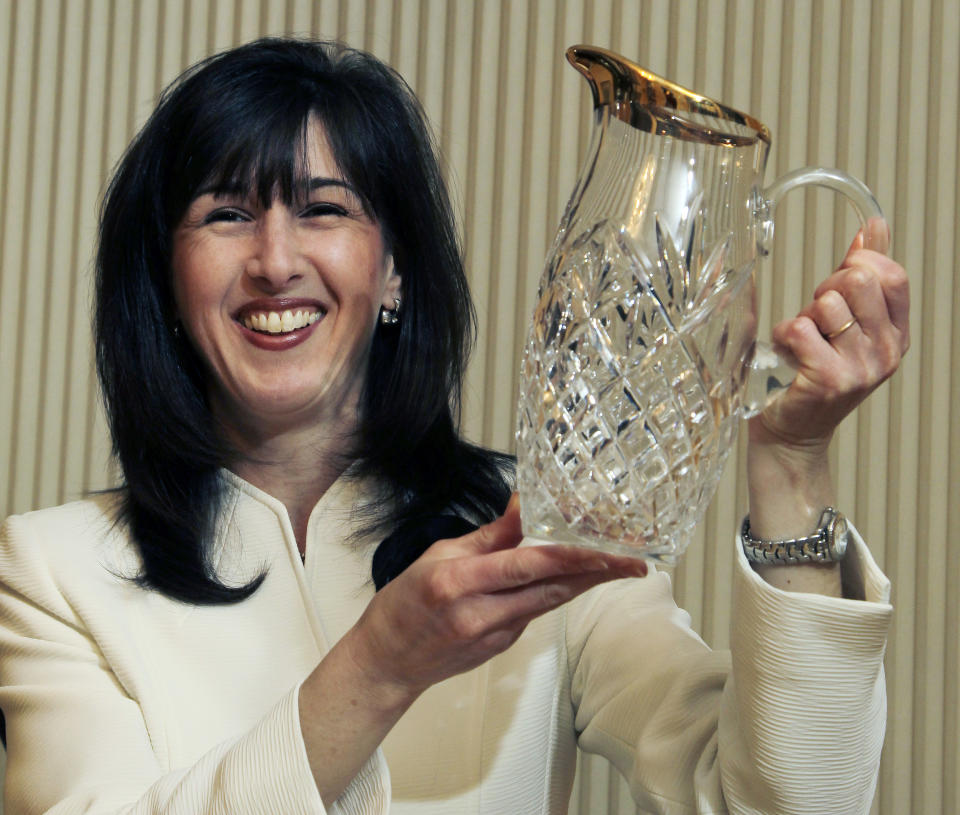 In this March 15, 2012 photo, Jodi R.R. Smith poses in her home in Marblehead, Mass., with a pitcher she and her husband received as a surprise wedding gift. The pitcher was not listed on Smith’s wedding registry, but over the years, she has come to love it. Smith, an etiquette expert, says it’s perfectly acceptable to give a wedding gift that’s not registered. (AP Photo/Elise Amendola)