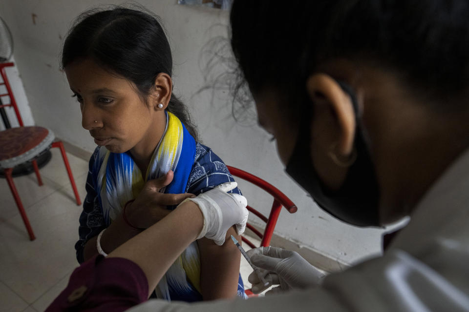 A woman receives her third dose of vaccine for COVID-19 at a private vaccination center in Gauhati, India, Sunday, April 10, 2022. India began offering booster doses of COVID-19 vaccine to all adults on Sunday but limited free shots at government centers to front-line workers and people over age 60. (AP Photo/Anupam Nath)