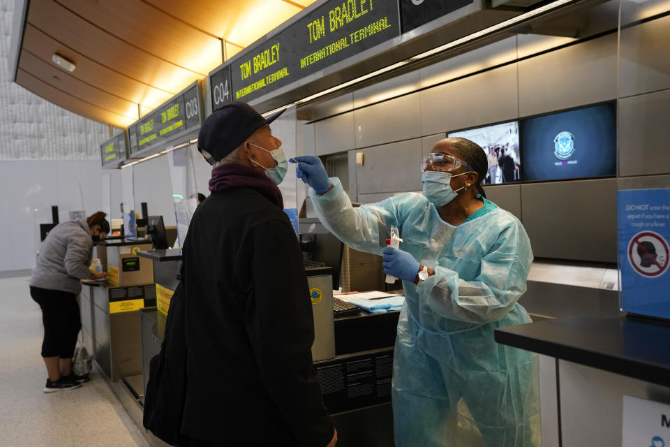 Licensed vocational nurse Caren Williams, left, collects a nasal swab sample from a traveler at a COVID-19 testing site at the Los Angeles International Airport in Los Angeles, on Monday, November 23, 2020. / Credit: Jae C. Hong / AP