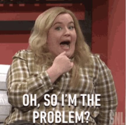 A woman with long hair in a plaid shirt gesturing towards herself with a caption that reads, "Oh, so I'm the problem?" from SNL