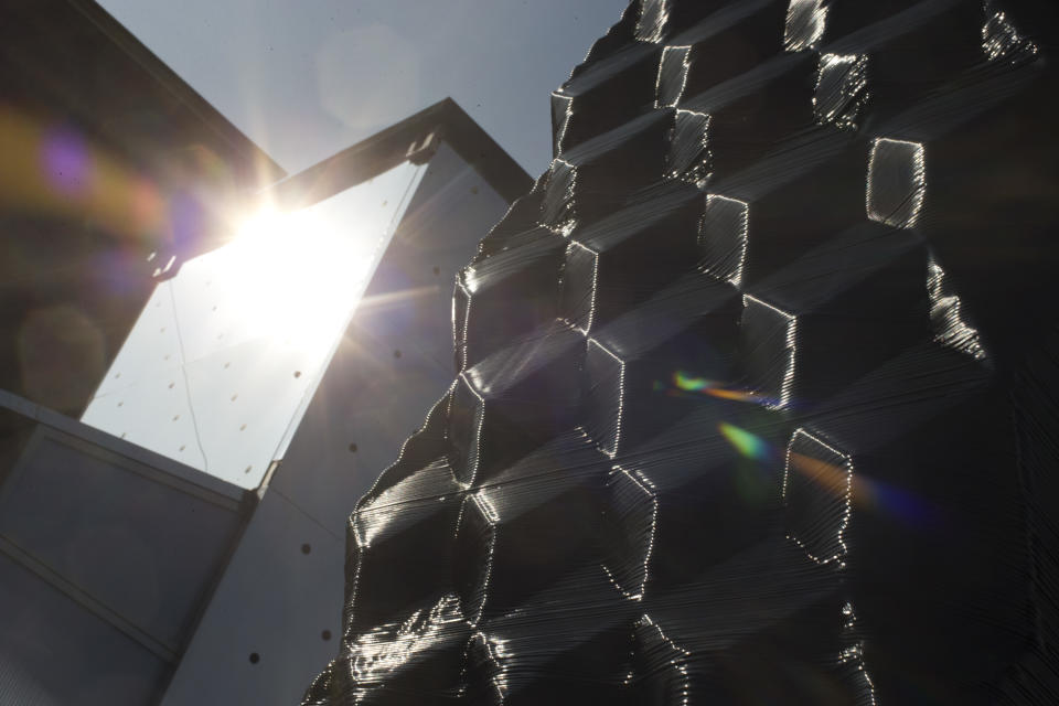 The sun bounces off a 3D printer which constructs the building blocks for a canal house, right, in Amsterdam, Netherlands, Thursday, March 13, 2014. Dutch architecture firm Dus has embarked on a project to build a 21st-century version of a classic Amsterdam canal house, printing it out piece by piece with an oversized 3-D printer, and then slotting them together like oversized Lego blocks. The goal is to discover and share the potential uses of 3-D printing in construction by creating new materials, trying out designs and testing building techniques. (AP Photo/Peter Dejong)