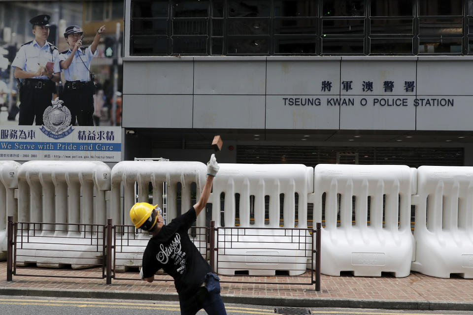 A protester throws a brick to the Tseung Kwan O police station during an anti-extradition bill protest in Hong Kong, Sunday, Aug. 4, 2019. Two planned protests in Hong Kong have kicked off as a sea of umbrellas filled the streets. (AP Photo/Vincent Thian)