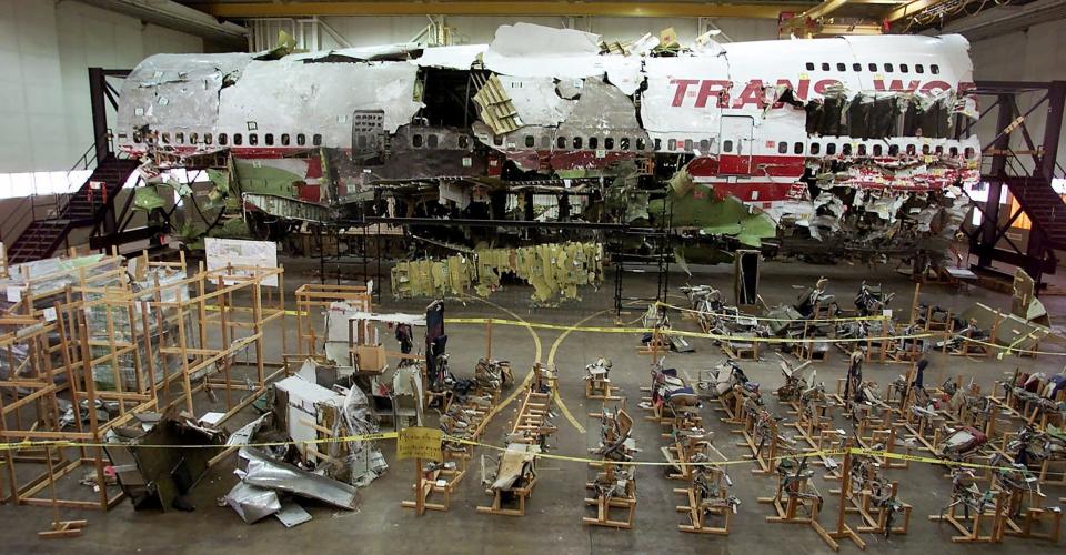 In this July 16, 2001, file photo, the seats, foreground, and wreckage of TWA Flight 800 sit in a hangar in Calverton, New York. The July 17, 1996, calamity was one of the most infamous air disasters in history. Some still debate findings that the Boeing 747 was brought down by a center fuel-tank explosion ignited by a spark from a short-circuit; a conclusion reached after the disintegrated jet was painstakingly put back together like a jigsaw puzzle.