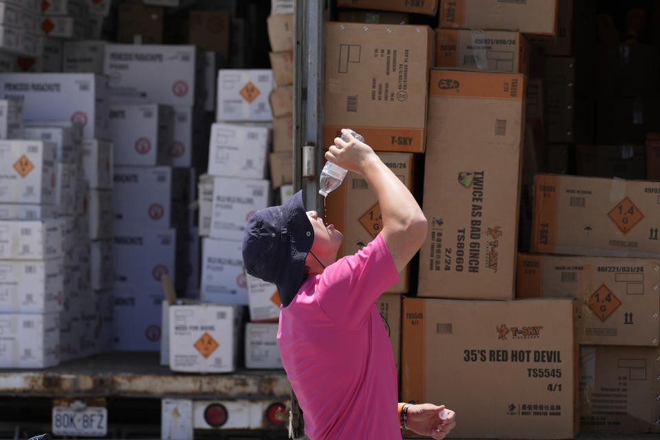 FILE - Wyatt Seymore pours the last drops of liquid from a water bottle into his mouth as he takes a break from unloading a stiflingly hot trailer of fireworks outside Powder Monkey Fireworks ahead of the opening of the stand, Monday, June 17, 2024, in Weldon Spring, Mo. While a heat wave brings the hottest temperatures so far this year to the Midwest and Northeast, forecasters also are discussing heat domes. What's the difference? A heat dome forms when high pressure in the upper atmosphere causes the air below it to sink, heat up and expand. (AP Photo/Jeff Roberson, File)