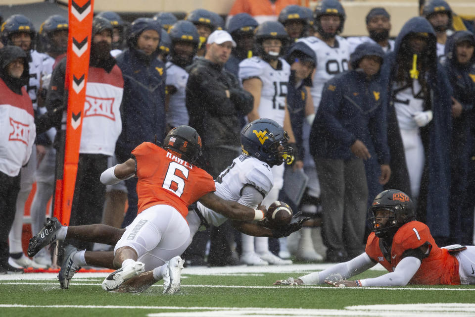 West Virginia wide receiver Jeremiah Aaron (4) dives past Oklahoma State safety Lyrik Rawls (6) for the ball during the second half of the NCAA college football game in Stillwater, Okla., Saturday Nov. 26, 2022. (AP Photo/Mitch Alcala)