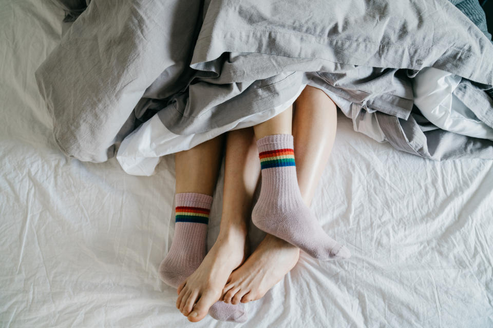 A couple is lying together in bed with their legs tangled up