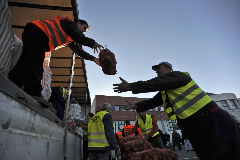 Farmers unload a truck with sacks of potatoes for sale at cost price in the northern Greek town of Katerini, Greece on Saturday, Feb. 25 2012. Farmers in northern Greece have joined forces with local residents to provide cheap produce to people whose family budgets have been slashed by the financial crisis, and also to help producers who say they are being squeezed by middlemen. Hundreds of families turned up Saturday in this northern Greek town to buy potatoes at massively reduced prices, sold directly by producers at cost price. (AP Photo/Nicolas Giakoumidis)