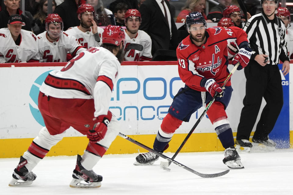 Washington Capitals right wing Tom Wilson (43) passes around Carolina Hurricanes defenseman Brent Burns, left, in the first period of an NHL hockey game, Friday, Jan. 5, 2024, in Washington. (AP Photo/Mark Schiefelbein)