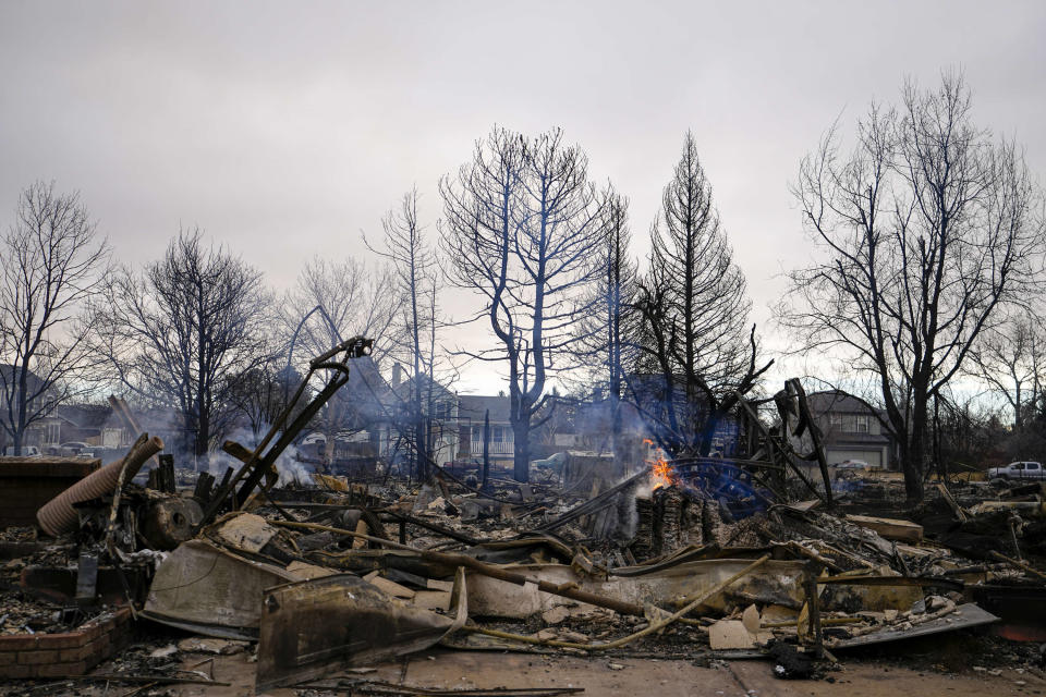 A fire still burns in a home destroyed by the Marshall Wildfire in Louisville, Colo., Friday, Dec. 31, 2021. (AP Photo/Jack Dempsey)