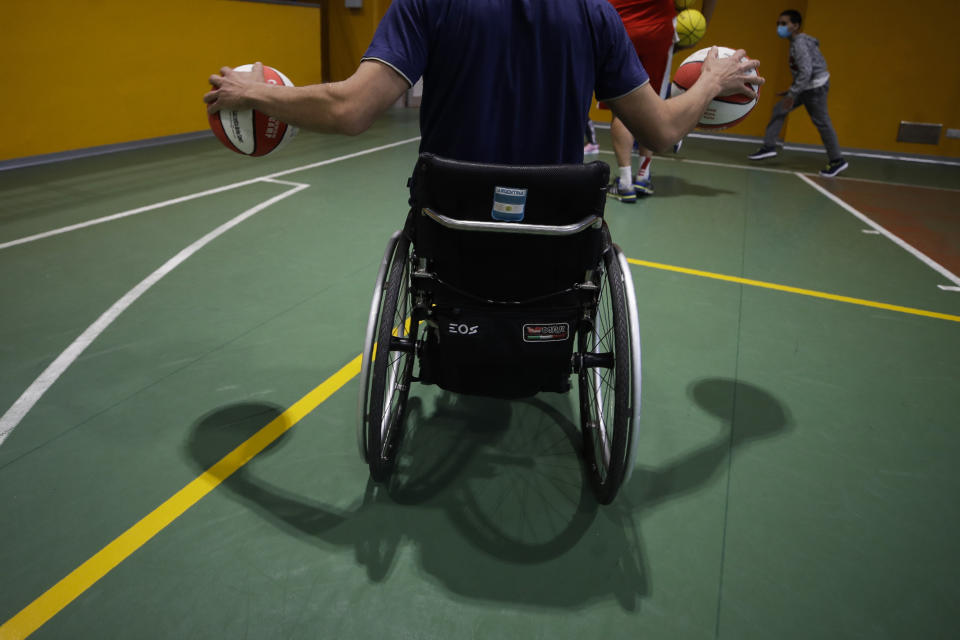 Adolfo Damian Berdun, of Argentina, a professional player and captain of the Argentine basketball Paralympic team, teaches children basketball at a primary school in Verano Brianza, outskirt of Milan, Italy, Tuesday, May 11, 2021. Four second-grade classes in the Milan suburb of Verano Brianza have been learning to play basketball this spring from a real pro. They also getting a lesson in diversity. Their basketball coach for the last month has been Adolfo Damian Berdun, an Argentinian-Italian wheelchair basketball champion. Berdun, 39, lost his left leg in a traffic accident at ag 13 in his native Buenos Aires, and he has visited many schools over the years to discuss how he has lived with his disability. (AP Photo/Luca Bruno)