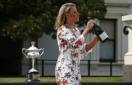 Germany's Angelique Kerber holds a bottle of champagne, with the women's singles trophy in the background, a day after winning her final match at the Australian Open tennis tournament, at the Government House in Melbourne, Australia, January 31, 2016. REUTERS/Jason Reed