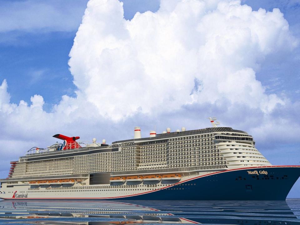 Carnival Cruise Line's Mardi Gras ship sailing in the ocean under a cloudy blue sky.