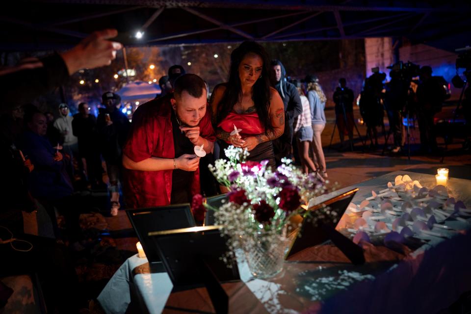 Two attendees look at pictures of Riley Strain during a candlelight vigil on Friday evening (AP)