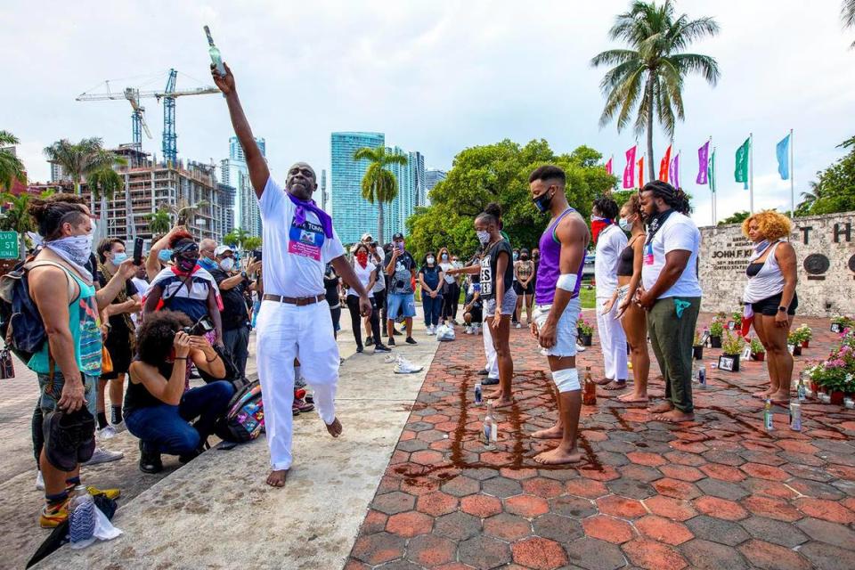 Little Haiti resident and Voudou Priest Ovida Alva, 49, sprays the crowd and demonstrators with a concoction of alcohol and fragrances during a “Say Their Names” protest at The Torch of Friendship in Miami, Florida on Saturday, July 4.